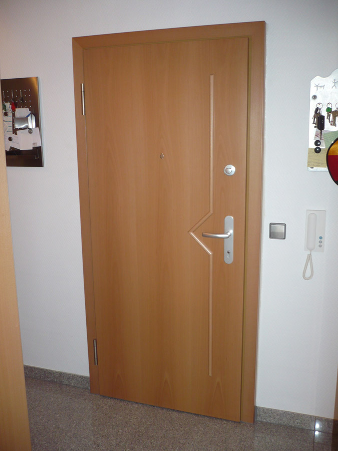 Wohnungstür in hellem Holzdekor mit asymmetrischen Metalleinlagen