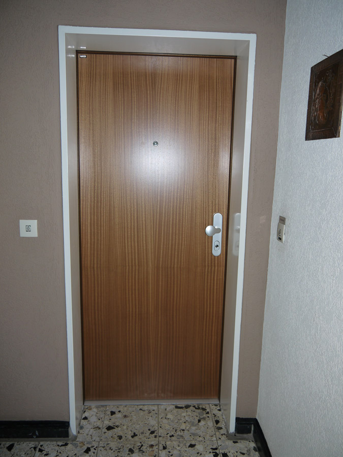 Schlichte Wohnungstür in dunklem Holzdekor mit weißem Nachrüstrahmen